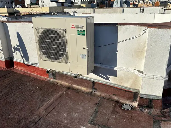Unidad exterior Mitsubishi Electric instalada en una azotea con los tejados de Madrid al fondo