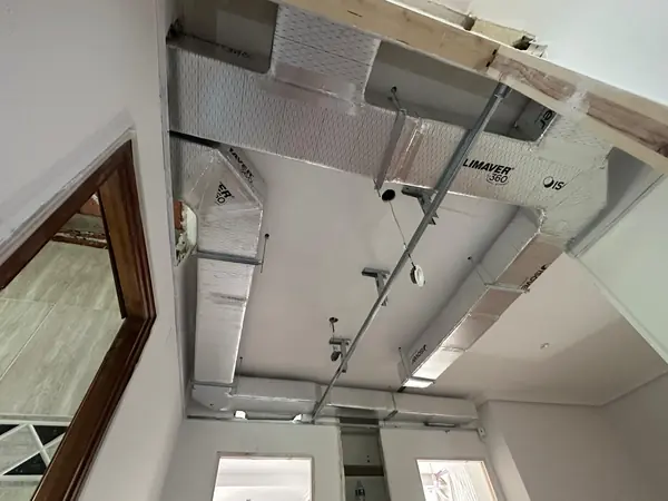 Red de conductos aislados repartida por el techo de una vivienda antes de colocar la escayola