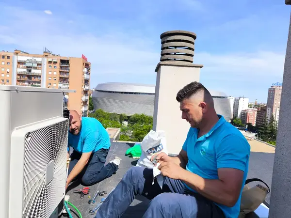 Los instaladores de BioClima21 montando una unidad exterior en una azotea junto al Bernabéu