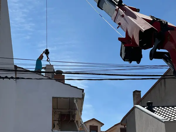 Camión grúa subiendo una unidad exterior hasta la azotea, donde la recibe un técnico de BioClima21