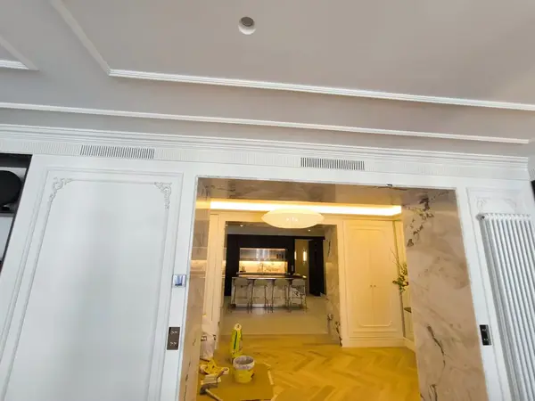 Rejilla lineal de impulsión integrada en la moldura de escayola de un salón