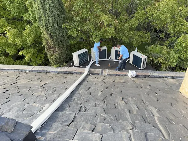 Dos técnicos de BioClima21 colocando las unidades exteriores sobre la cubierta de pizarra de un chalet