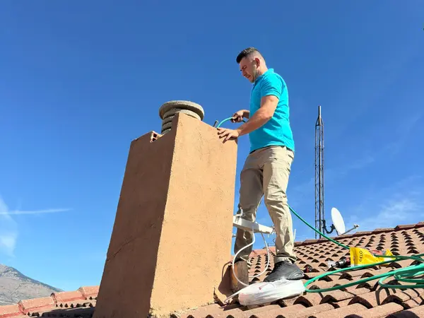 Técnico de BioClima21 pasando la instalación junto a la chimenea del tejado