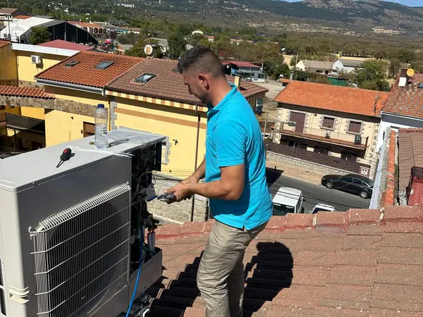 Técnico de BioClima21 conectando una unidad exterior sobre un tejado de teja, con la sierra al fondo