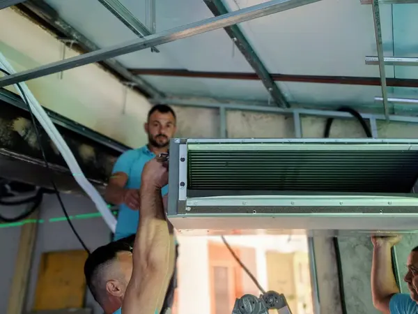 Instaladores de BioClima21 colgando una unidad de conductos del forjado antes de cerrar el falso techo